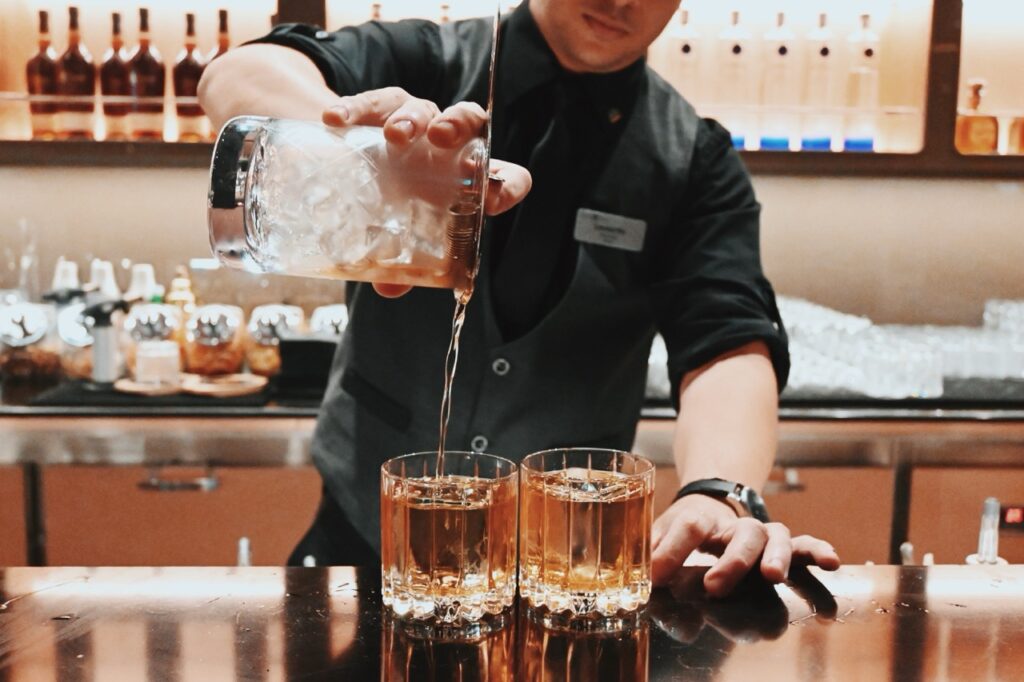Bartender pours a cocktail into a glass