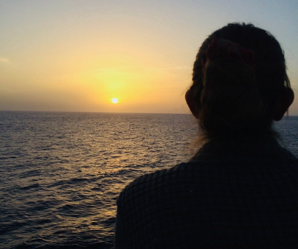 Allie looks out into the ocean with the sunset
