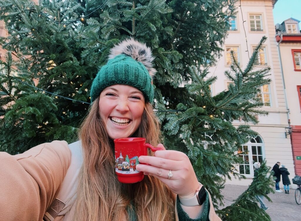 Allie Hubers smiles while holding a Christmas mug at a market in Heidelberg, Germany