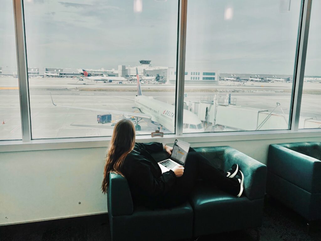 Allie sits in an airport lounge and looks out to a Delta plane